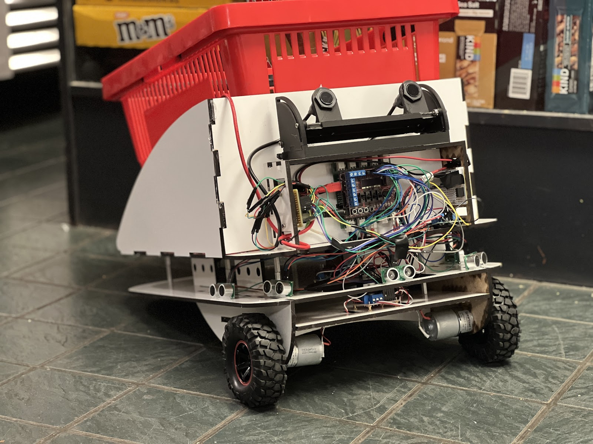 Assembled Following Basket prototype with exposed wiring, ultrasonic sensors, and a red shopping basket on top